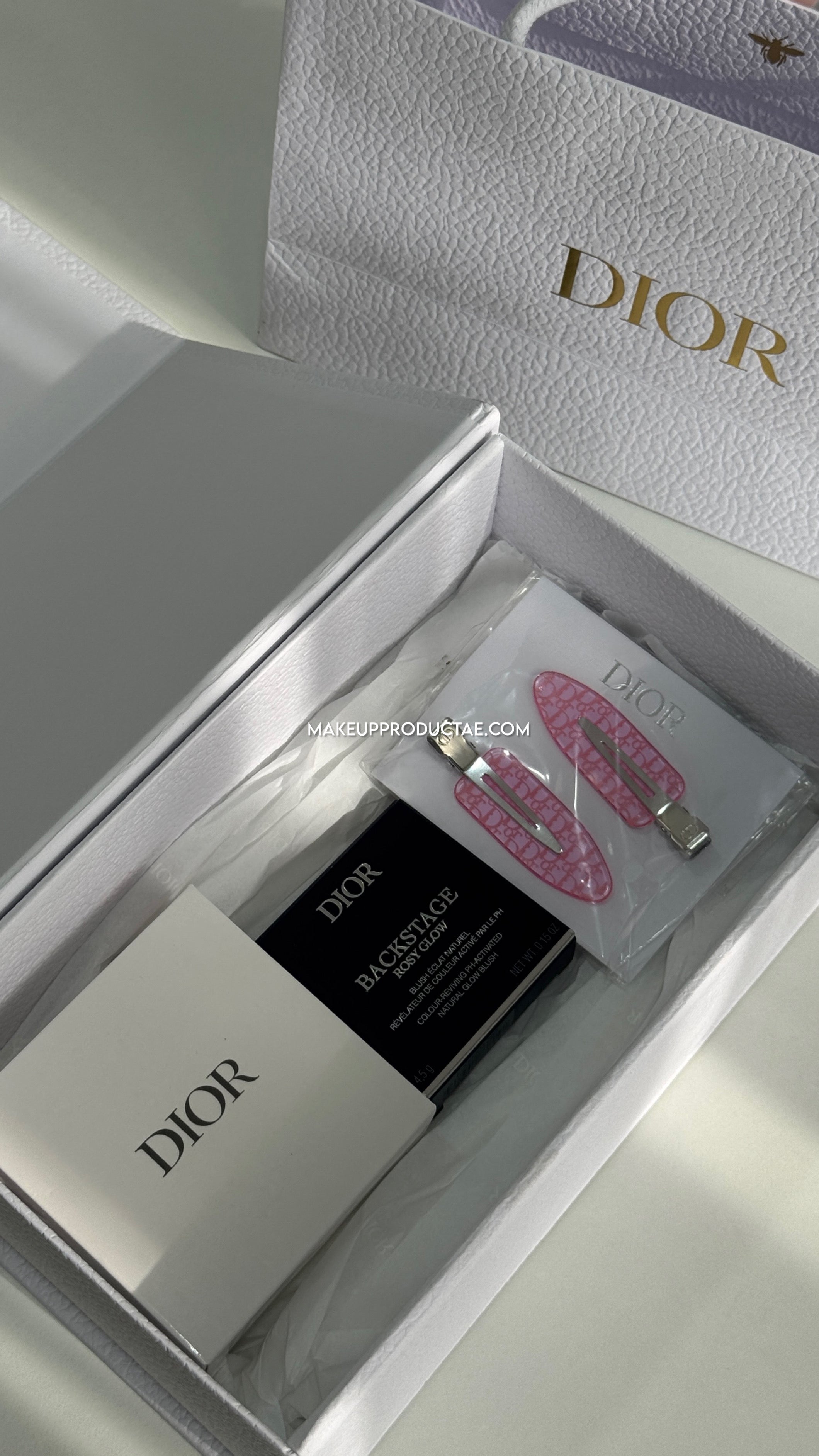 Dior cosmetic case with pink lip-shaped item and branded box on a light background