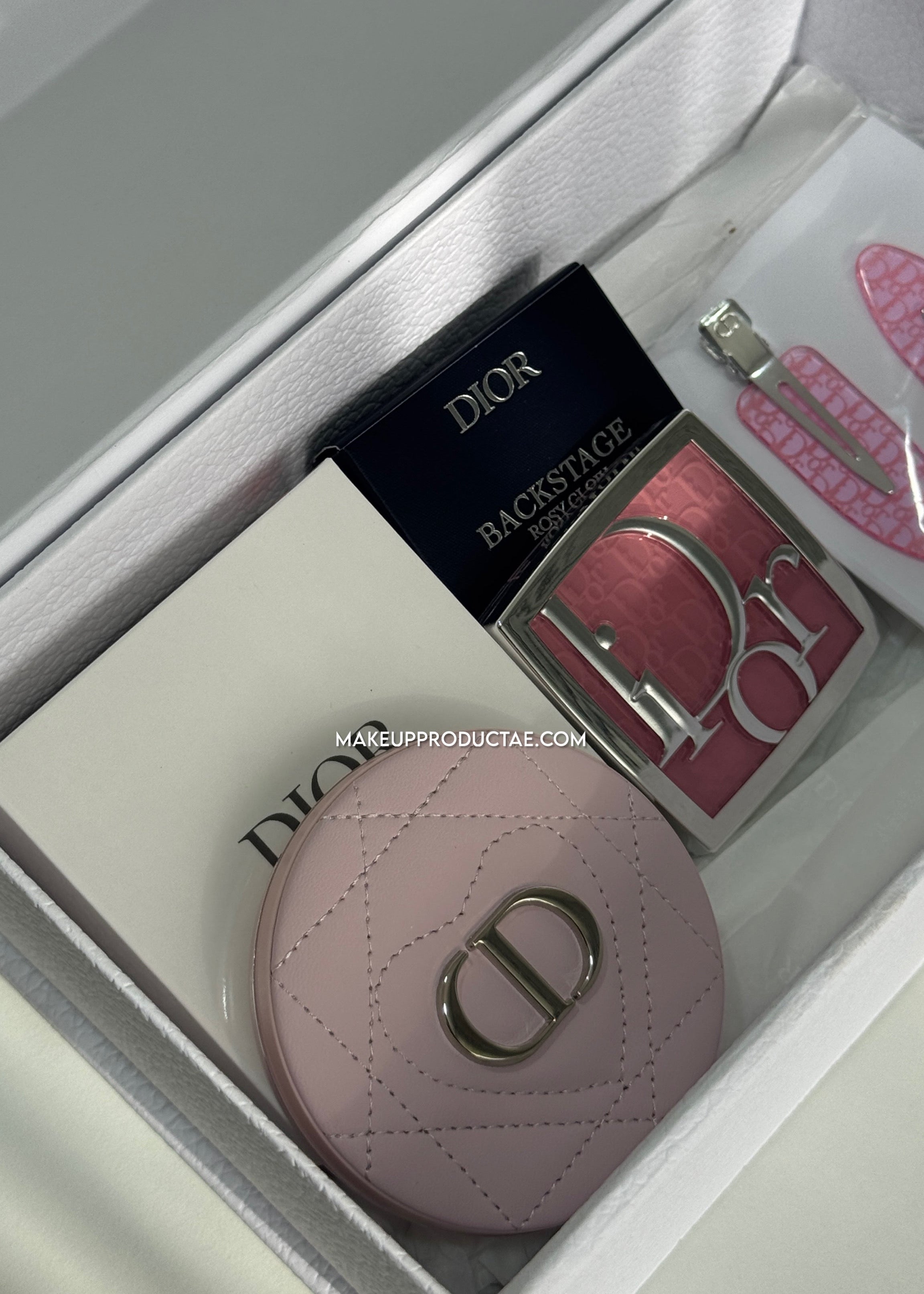 Dior makeup items including a pink compact and a palette in an open box.