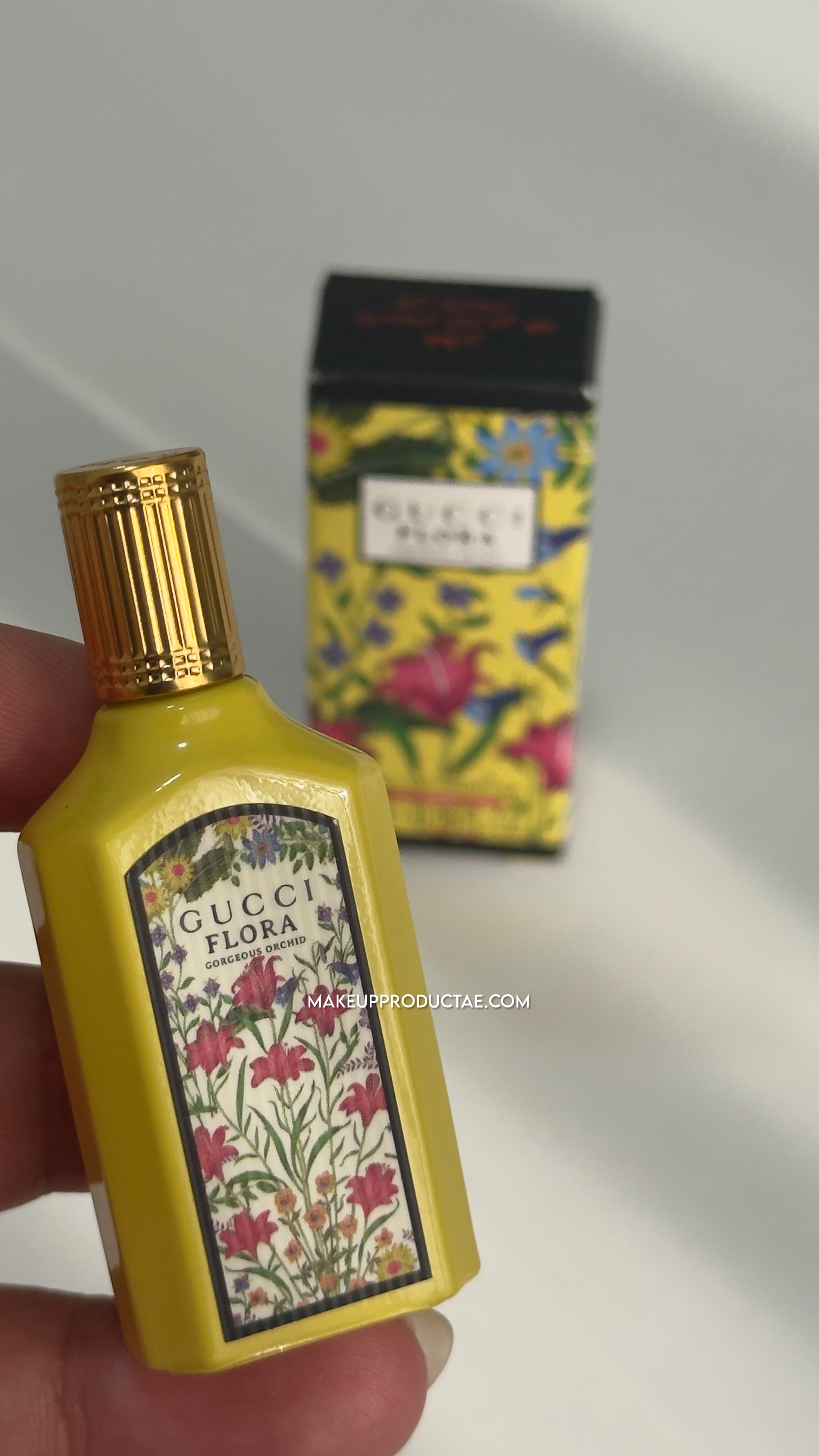 Gucci Flora perfume bottle held in hand with packaging in the background