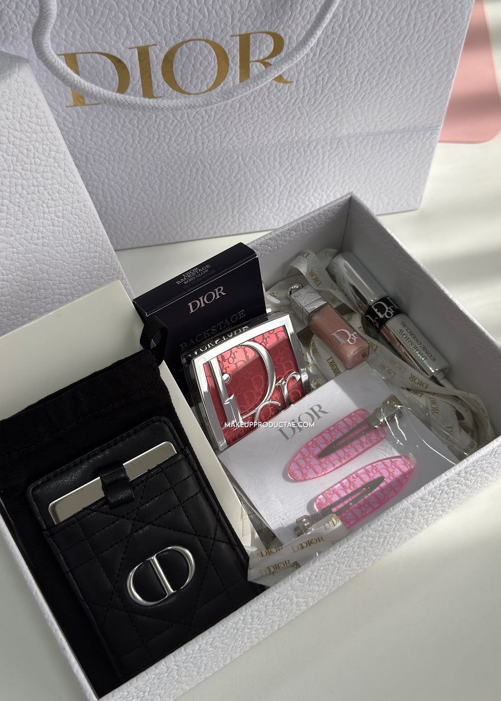 Dior product set including a card holder, wallet, and other items in a branded box.