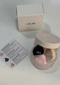 Dior powder foundation compact with a beige lid, shown open next to its cream-colored Dior box and a small instruction card on a light gray surface.