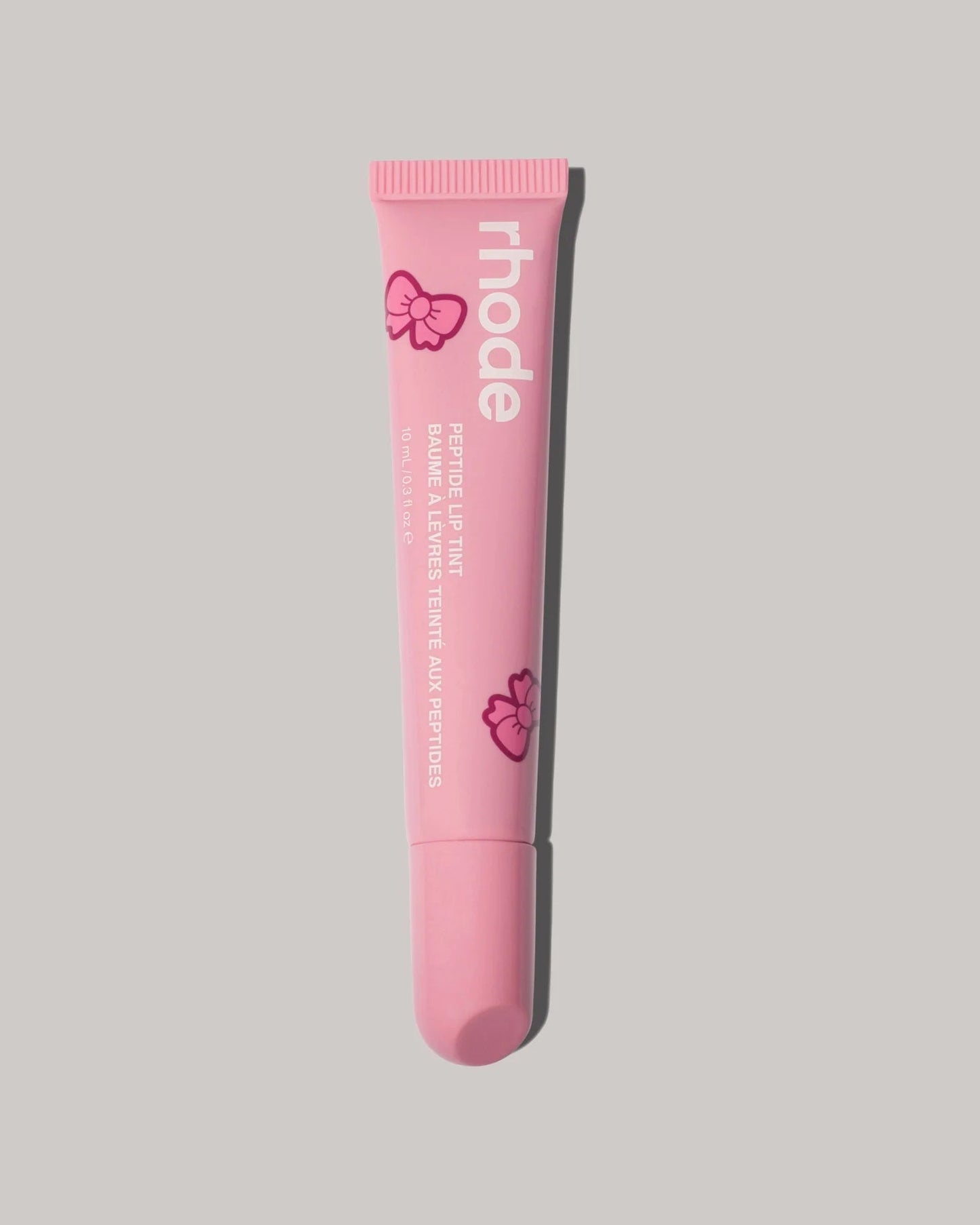 Pink lip balm tube with 'rhode' branding on a gray background