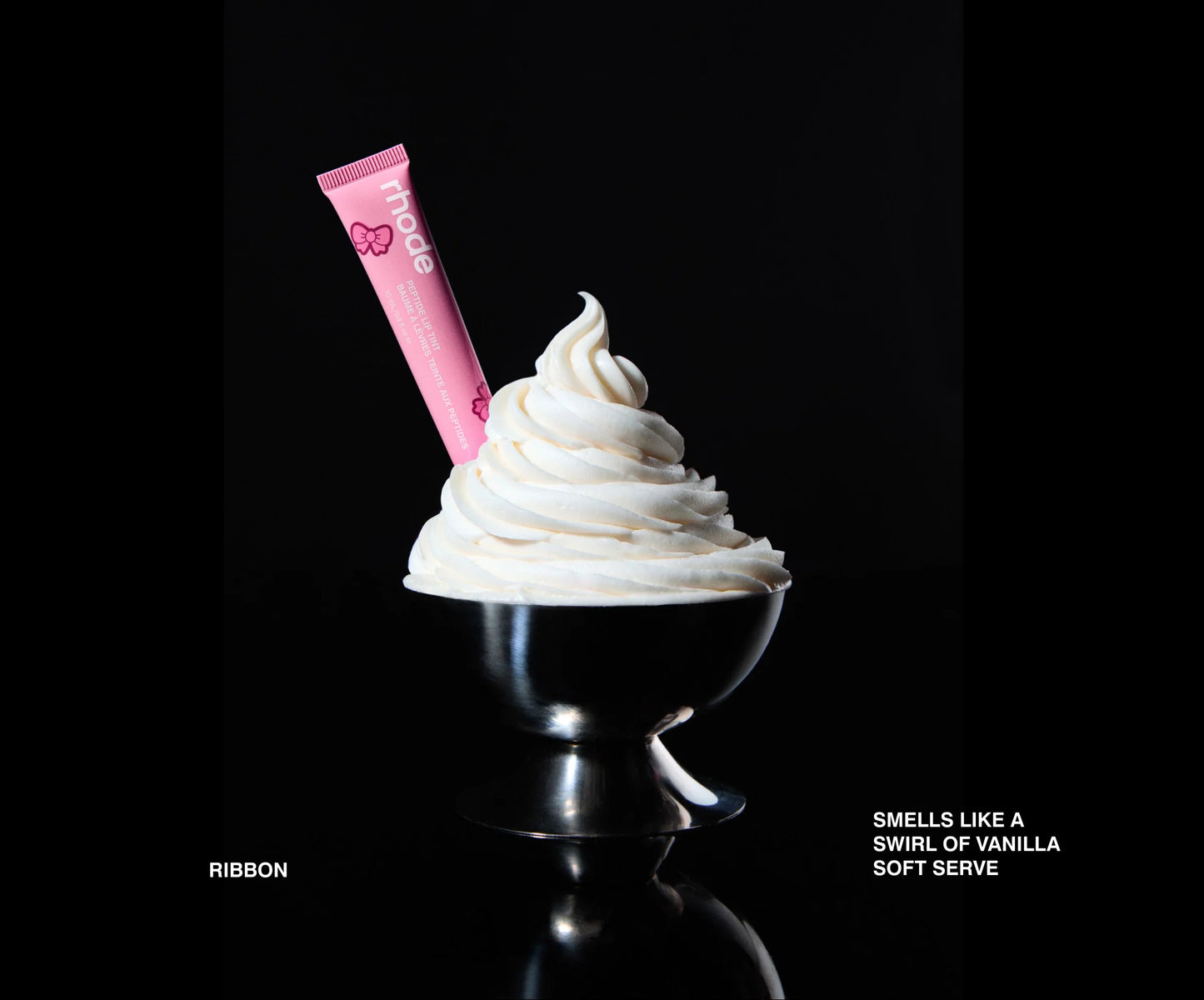 Pink lip balm on a swirl of vanilla soft serve ice cream against a black background