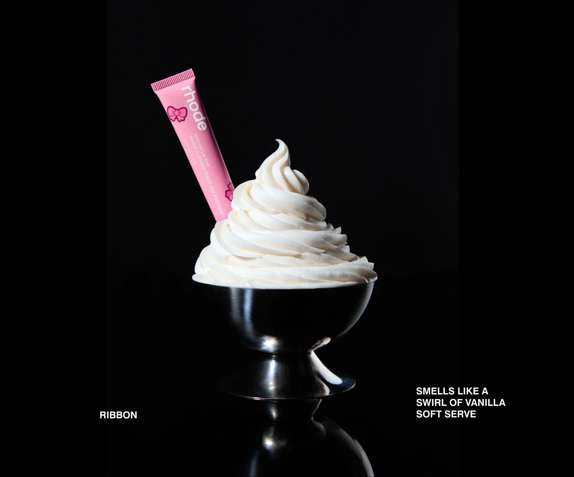 Pink lip balm on a swirl of vanilla soft serve ice cream against a black background